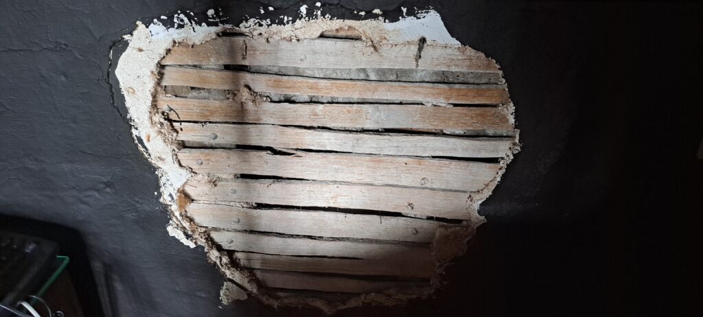 Area of damaged plaster in the Parker Room during repair. This shows wattle of a more common kind in the house.