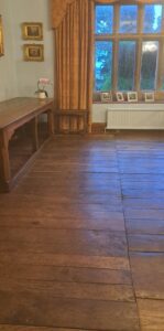 The seam in the oak floor boards runing north-south in the Blue Room