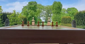 A chess board in chess court at Soulton Hall; the finials of the chess court gate sand in for two missin pawns on a modern board