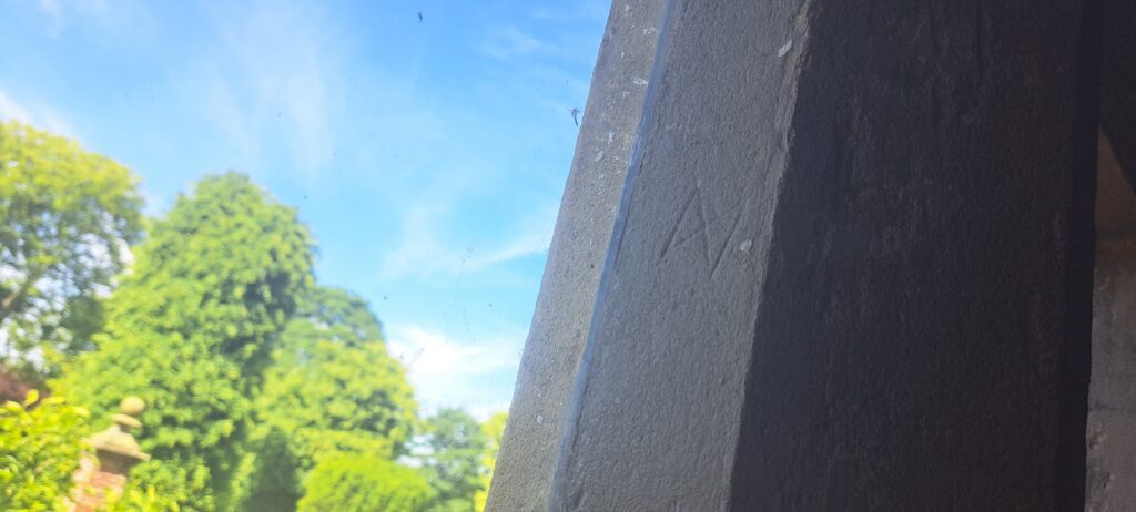 Triangles meeting at a point drawn within a square, a carving in the north window of the Hall Hall in Soulton Hall