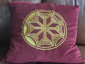 a dark red cushion with the Soulton Hall dance pattern on it in gold