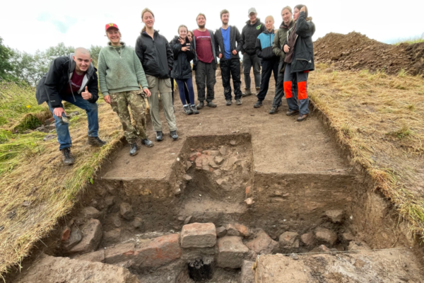 Archaeologists stand by a trench exposing a timber bridge and stone footings on Soulton Mound