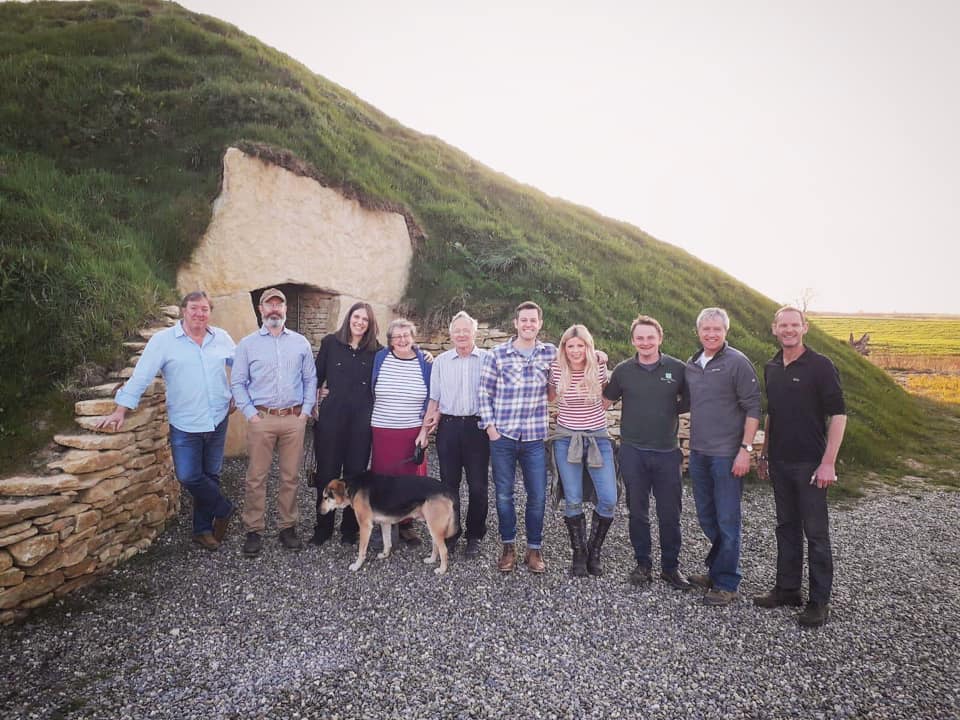 Presenters, crew and the Soulton Team stand outside the Soulton Long Barrow - a mound with turf on top and a stone doorway.