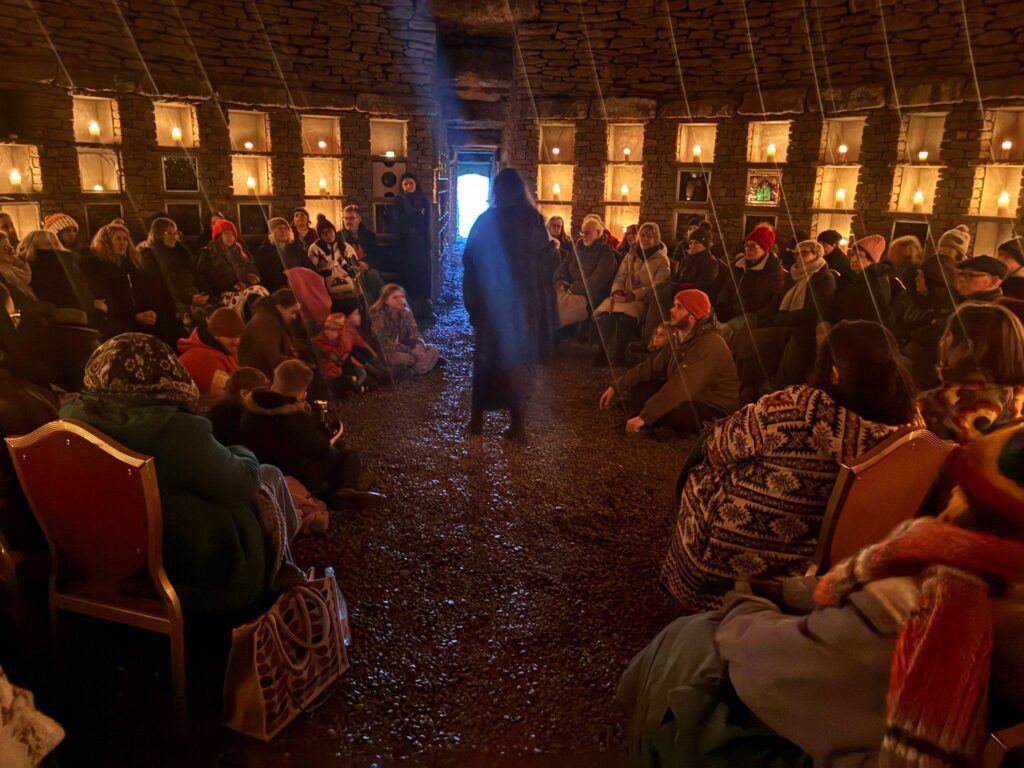 Community gathered within the stone corbeled chamber, sharing stories and songs as the winter solstice approaches at Soulton Long Barrow Winter Solstice Event 2025