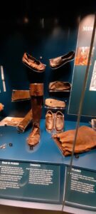 The display of delicate shoes and boots, clearly not intended for the rigors of daily work on deck, reveals a surprising culture of courtly dress that persisted even on board, proving that the officers sought to maintain their social standing through fine attire regardless of their surroundings.