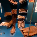The display of delicate shoes and boots, clearly not intended for the rigors of daily work on deck, reveals a surprising culture of courtly dress that persisted even on board, proving that the officers sought to maintain their social standing through fine attire regardless of their surroundings.