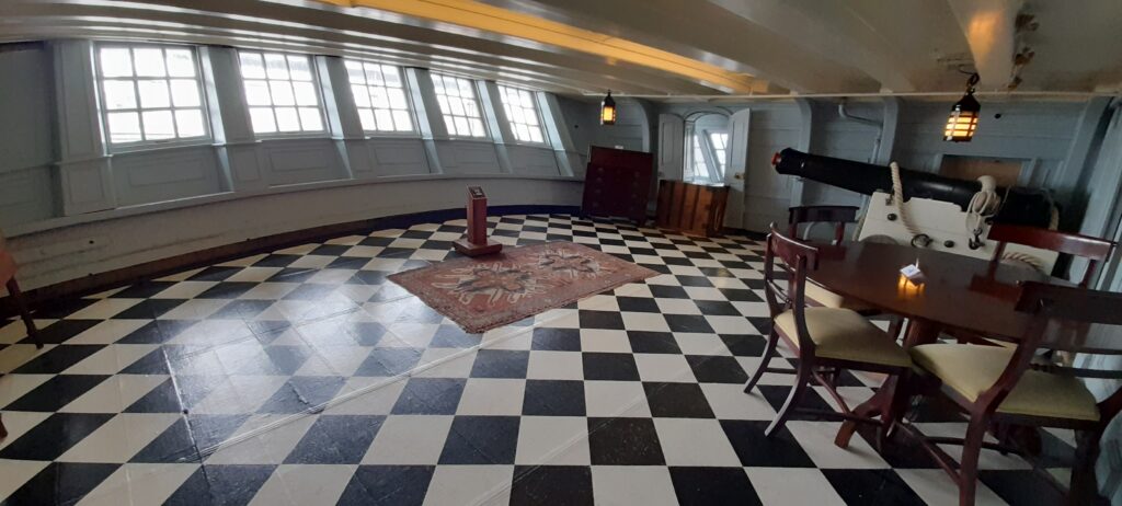 Situated directly above Vice-Admiral Nelson’s quarters, Captain Thomas Hardy’s day cabin was a bright, orderly, and geometric space at the stern that served as the crisp administrative center for managing the daily operations of the flagship.
