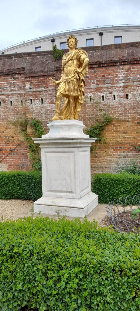 Tucked away in the Porter's Garden at the historic dockyard, the gleaming gold-gilt statue of King William III in the grand attire of a Roman Emperor—inscribed by a commoner as "the best of kings"—reveals how the creation of a hero can also be driven from the ground up, as ordinary citizens use public monuments to shape the national legacy.